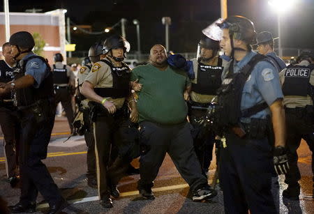 Police hold a protester who was detained in Ferguson, Missouri, August 10, 2015. REUTERS/Rick Wilking