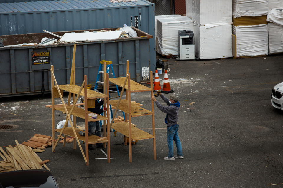 Workers build shelves for a makeshift morgue outside Wyckoff Heights Medical Center in Brooklyn, New York, on March 30, as seen from an apartment building across the street. | Benjamin Norman for TIME