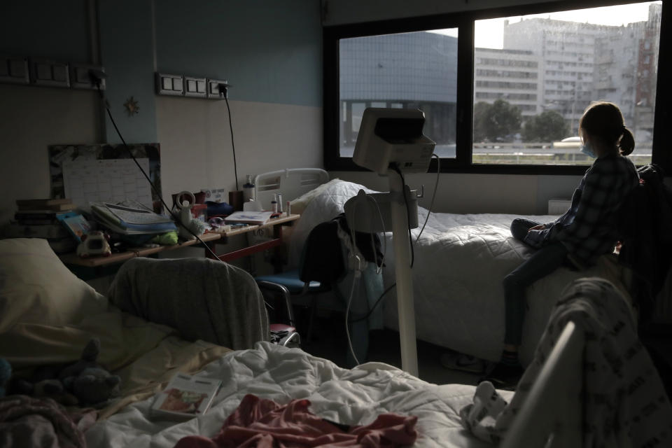 A young girl looks out the window of her room in the pediatric unit of the Robert Debre hospital, in Paris, France, Tuesday, March 2, 2021. A year into the coronavirus pandemic, increasing numbers of children are coming apart at the seams, their mental health shredded by the traumas of deaths, sickness and job losses in their families, the disruptions of lockdowns and curfews, and a deluge of anxieties poisoning their fragile young minds. (AP Photo/Christophe Ena)