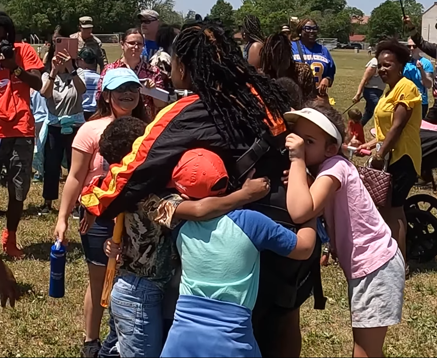 Bowley Elementary School Principal Latonya Leeks hugs students on Polo Field after Leeks made a tandem jump on Friday, May 12, 2023, to celebrate Leeks' students exceeding their reading goals.