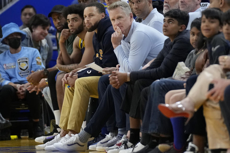 Injured Golden State Warriors guard Stephen Curry, middle left, and head coach Steve Kerr, middle, watch from the bench during the first half of the team's NBA basketball game against the Minnesota Timberwolves in San Francisco, Sunday, Feb. 26, 2023. (AP Photo/Jeff Chiu)
