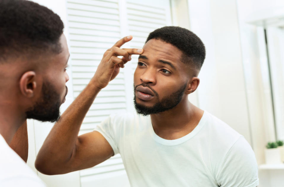 worried man looking at wrinkles in mirror