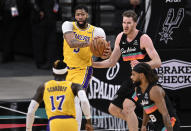 Los Angeles Lakers' Anthony Davis, left rear, looks to pass to teammate Dennis Schroeder (17) as he is defended by San Antonio Spurs' Patty Mills (8) and Jakob Poeltl during the first half of an NBA basketball game, Friday, Jan. 1, 2021, in San Antonio. (AP Photo/Darren Abate)