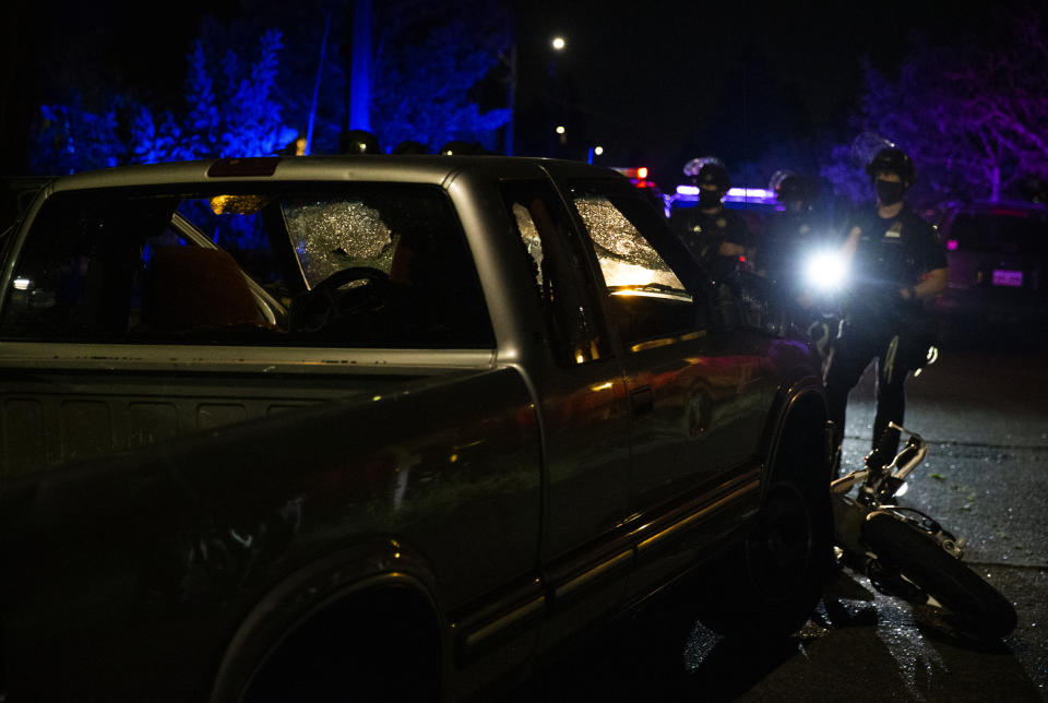 A pickup truck was abandoned several blocks west after its driver accelerated towards the crowd, hitting and dragging a motorcycle during a protest in Portland, Ore., on Tuesday, Aug. 4, 2020. A riot was declared early Wednesday during demonstrations in Portland after authorities said people set fires and barricaded public roadways.(Dave Killen /The Oregonian via AP)