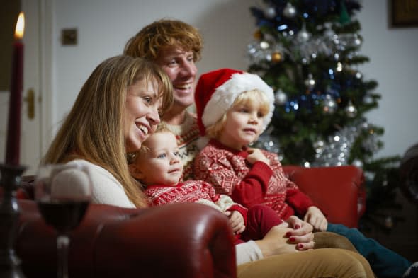 Young family in living room watching television on Christmas day.