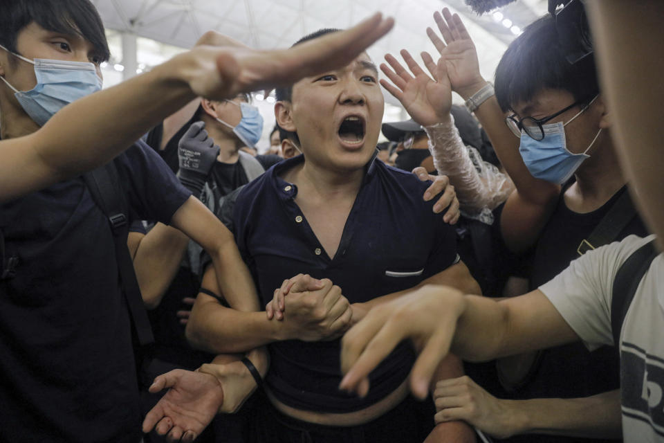 Protesters detaiN a man, who protesters claimed was a Chinese undercover agent during a demonstration at the Airport in Hong Kong, Tuesday, Aug. 13, 2019. Riot police clashed with pro-democracy protesters at Hong Kong's airport late Tuesday night, a chaotic end to a second day of demonstrations that caused mass flight cancellations at the Chinese city's busy transport hub. (AP Photo/Vincent Yu)