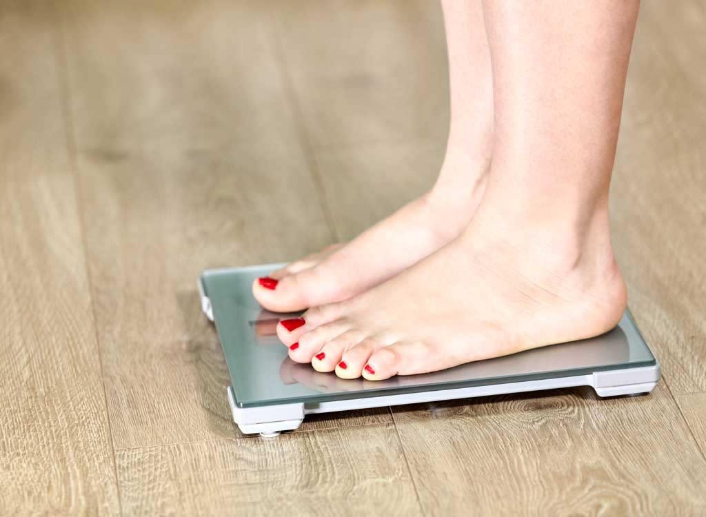 Top view of feet on weighing scale. Women weigh on a weight balance scale  after diet control. Healthy body weight. Weight and fat loss concept. Weight  measure machine. Body Mass Index or