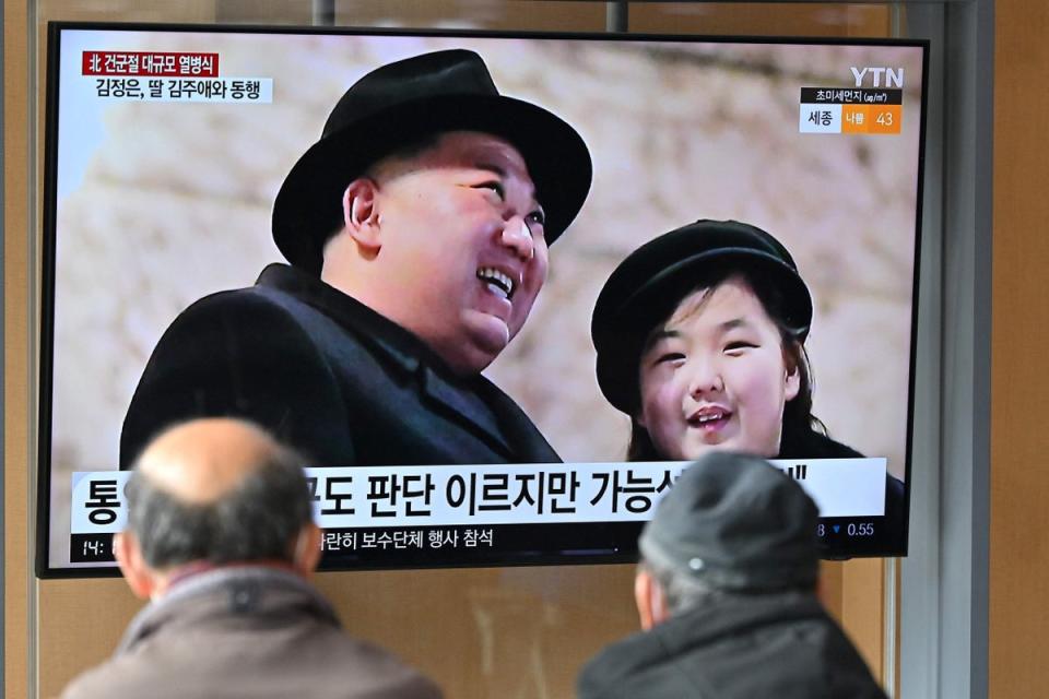 People at a railway station Seoul watch a TV news broadcast of the military parade held in Pyongyang (AFP via Getty Images)