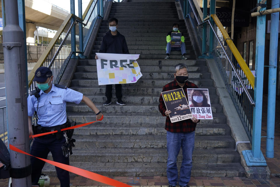 Pro-democracy activists, including Lee Cheuk-Yan, right, hold placards with the picture of the Chinese citizen journalist Zhang Zhan as they march to the Chinese central government's liaison office, in Hong Kong, Monday, Dec. 28, 2020. They demanded the release of the 12 Hong Kong activists detained at sea by Chinese authorities. (AP Photo/Kin Cheung)