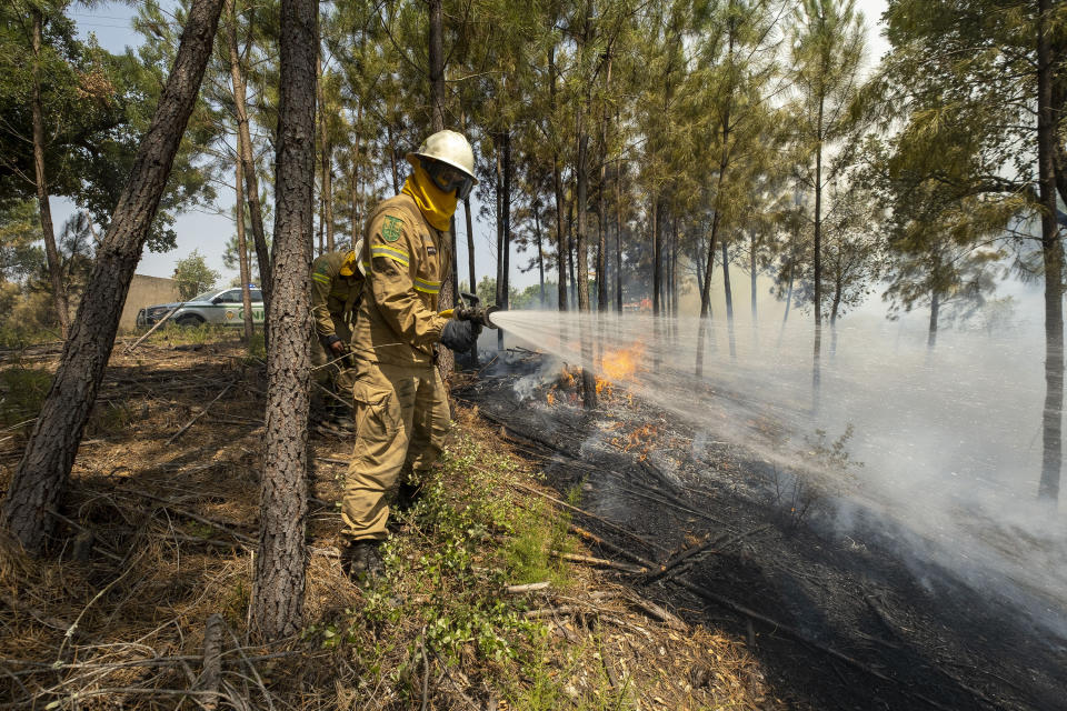 Firefighters try to extinguish a wildfire near Colos village, in central Portugal on Monday, July 22, 2019. More than 1,000 firefighters battled Monday in torrid weather against a major wildfire in Portugal, where every summer forest blazes wreak destruction. (AP Photo/Sergio Azenha)