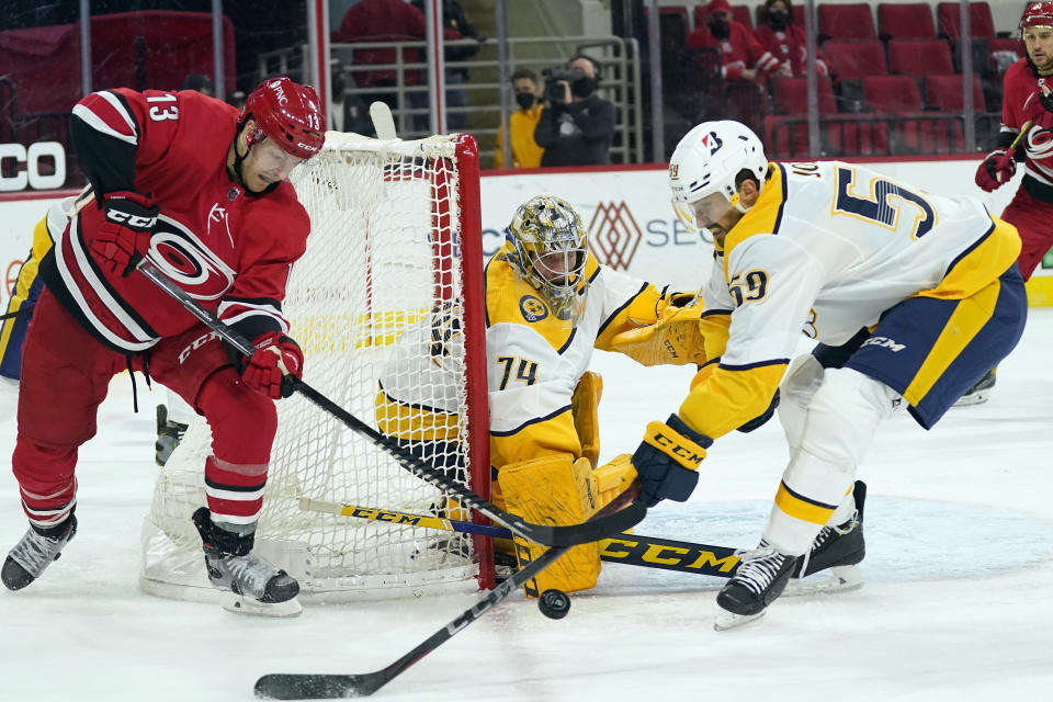 Nashville Predators goaltender Juuse Saros (74) and defenseman Roman Josi (59) defend against Carolina Hurricanes left wing Warren Foegele (13) during the second period of an NHL hockey game in Raleigh, N.C., Saturday, April 17, 2021. (AP Photo/Gerry Broome)