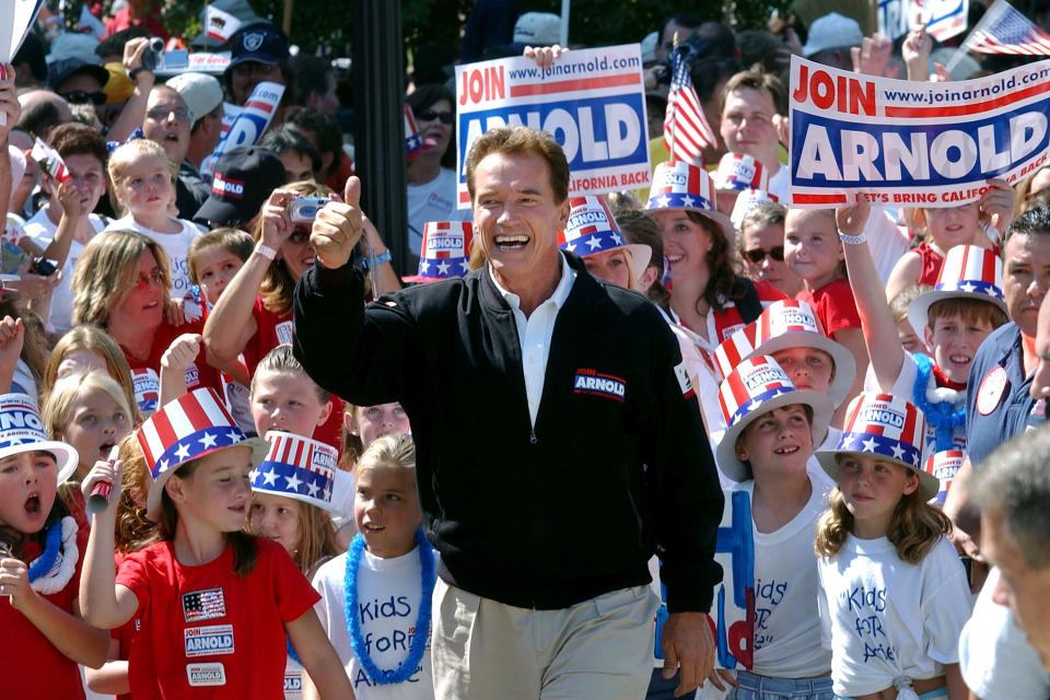 FILE - In this Oct. 5, 2003, file photo, then-Republican candidate for California governor Arnold Schwarzenegger walks up the steps to the state Capitol surrounded by children and waving to supporters during a campaign rally in Sacramento, Calif. No candidate of Schwarzenegger's fame has yet emerged in the expected 2021 recall election against Democratic Gov. Gavin Newsom. (AP Photo/Steve Yeater, File)