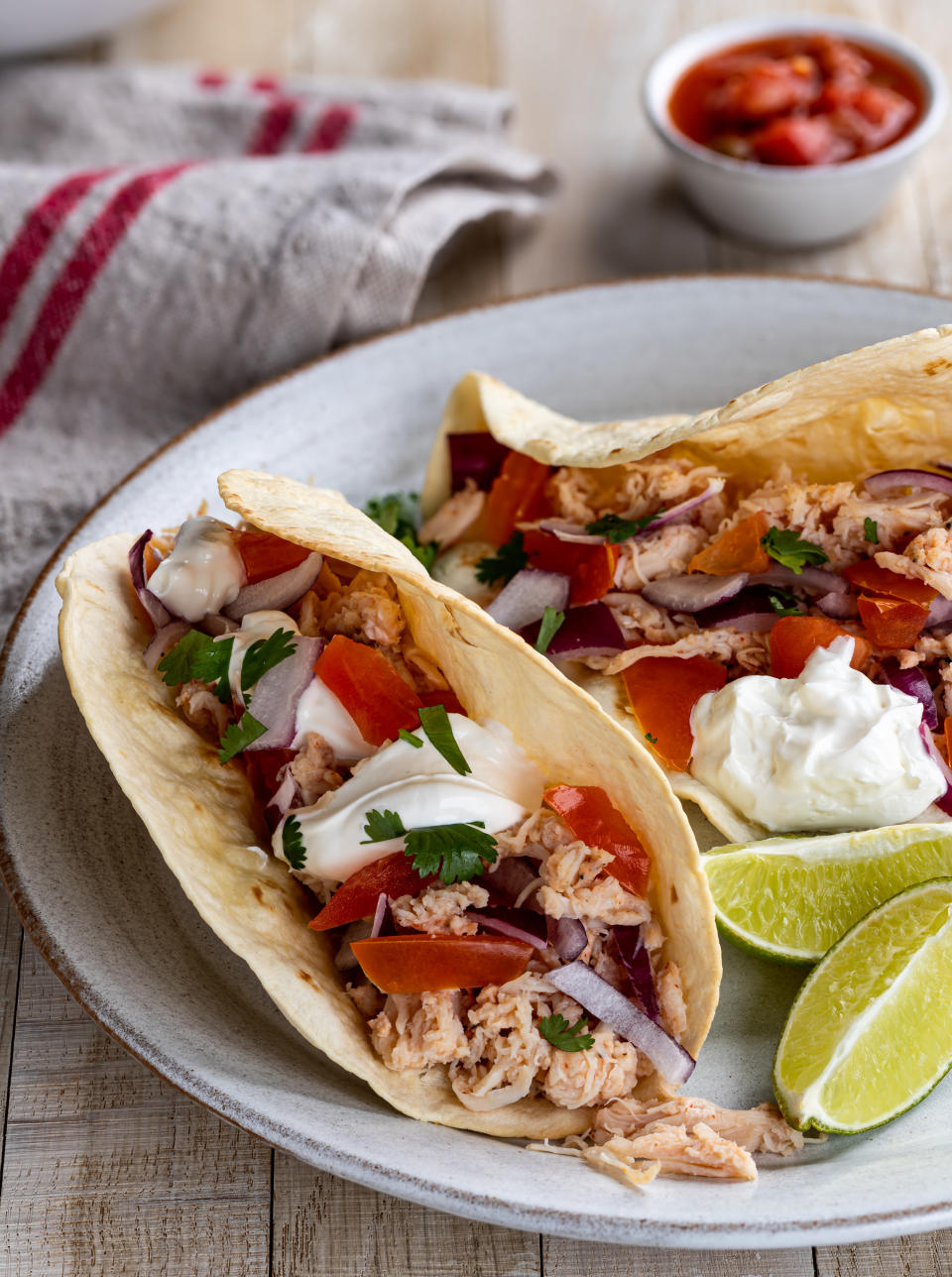 plate of chicken tacos with sliced limes on the side