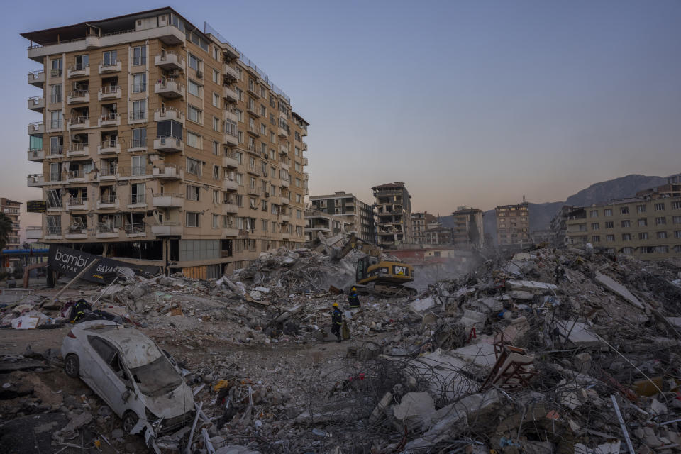 An excavator works among the debris of collapsed buildings during the earthquake in Antakya, southeastern Turkey, Tuesday, Feb. 14, 2023. The death toll from the earthquakes of Feb. 6, that struck Turkey and northern Syria is still climbing. (AP Photo/Bernat Armangue)