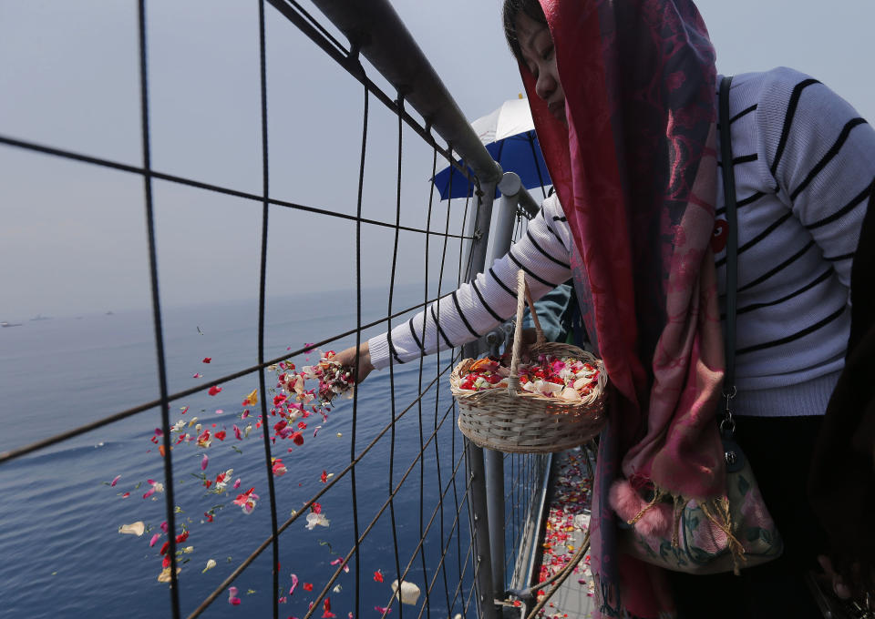 A relative sprinkles flowers for victims in the crashed Lion Air flight 610 aboard an Indonesia Navy ship in the waters where the airplane is believed to have crashed in Tanjung Karawang, Indonesia, Tuesday, Nov. 6, 2018. (AP Photo/Tatan Syuflana)