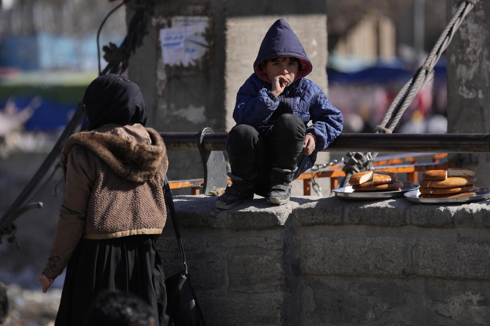 A boy selling bread watches Muslims attending Friday Prayer in Kabul, Afghanistan, Friday, Feb. 11, 2022. (AP Photo/Hussein Malla)