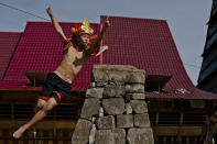 NIAS ISLAND, INDONESIA - FEBRUARY 22: A villager wearing traditional costume jumps over a stone in front of their ancient houses in Bawomataluwo village on February 22, 2013 in Nias Island, Indonesia. Stone Jumping is a traditional ritual, with locals leaping over large stone towers, which in the past resulted in serious injury and death. Stone jumping in Nias Island was originally a tradition born of the habit of inter tribal fighting on the island of Nias. (Photo by Ulet Ifansasti/Getty Images)