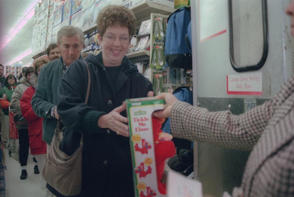 Carol Robinson of Center Township is all smiles in December 1996 as she received a Tickle Me Elmo doll from Darria King, assistant manager at the Hills store in Hopewell Township. Robinson and everyone in line behind her braved the cold for a chance at the store’s few remaining Elmo dolls, which were being sold for about $25. [Deborah Cannon/BCT file]