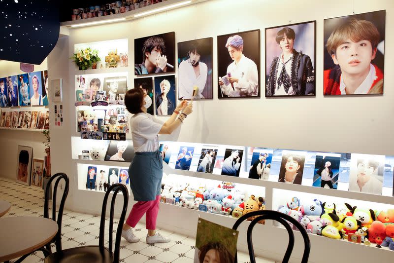 Cafe owner Kim Eun-hee, fan of K-pop boy band BTS, wipes the dust off the picture frame in her cafe in Seoul