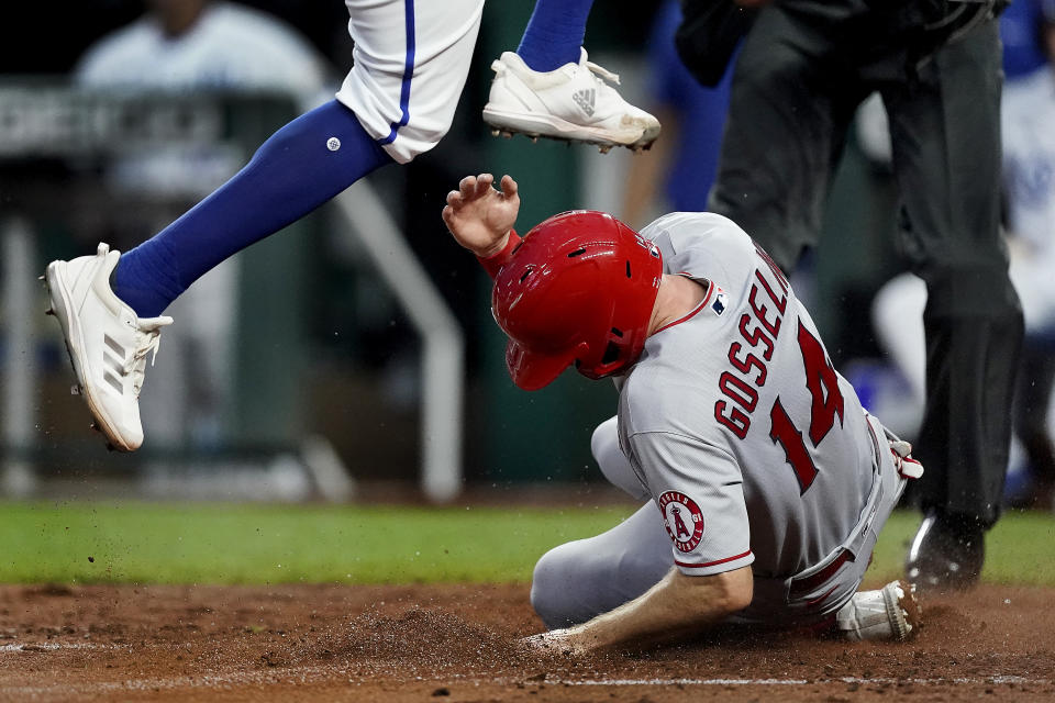 Kansas City Royals relief pitcher Amir Garrett leaps over Los Angeles Angels' Phil Gosselin (14) after Gosselin scored on Garrett's wild pitch during the fifth inning of a baseball game Tuesday, July 26, 2022, in Kansas City, Mo. (AP Photo/Charlie Riedel)