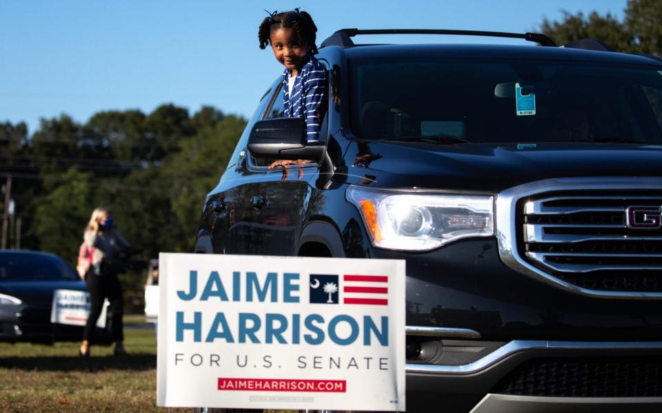 A young supporter of Democratic candidate for Senate Jaime Harrison looks on from her vehicle as he speaks during a socially distanced drive-in rally - AFP