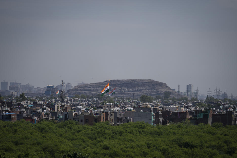 Indian national flags flutter over a residential area in front of a garbage dump in New Delhi, India, Friday, Aug. 5, 2022. As India, the world’s largest democracy, celebrates 75 years of independence on Aug. 15, its independent judiciary, diverse media and minorities are buckling under the strain, putting its democracy under pressure. Experts and critics partly blame Prime Minister Narendra Modi's populist government for this backsliding, accusing him of using unbridled political power to undermine democratic freedoms and preoccupying itself with pursuing a Hindu nationalist agenda. (AP Photo/Altaf Qadri)