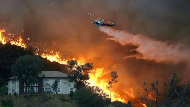 PHOTO: A firefighting helicopter makes a water drop as the Holy Fire burns near homes, Aug. 9, 2018, in Lake Elsinore, Calif. (Mario Tama/Getty Images)