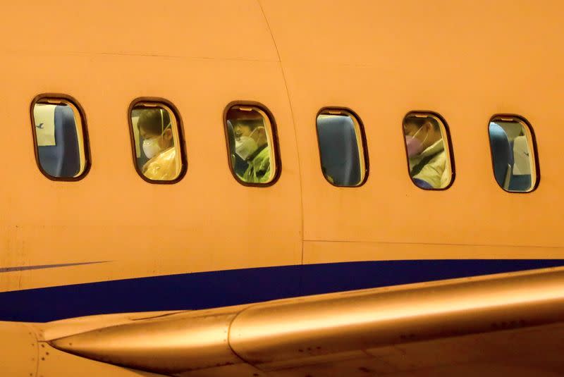 Passengers wearing face masks are seen on a Xiamen Airlines airplane before getting off the charter flight sent by the Chinese government to bring home Hubei residents from Thailand's Bangkok, at Wuhan Tianhe International Airport