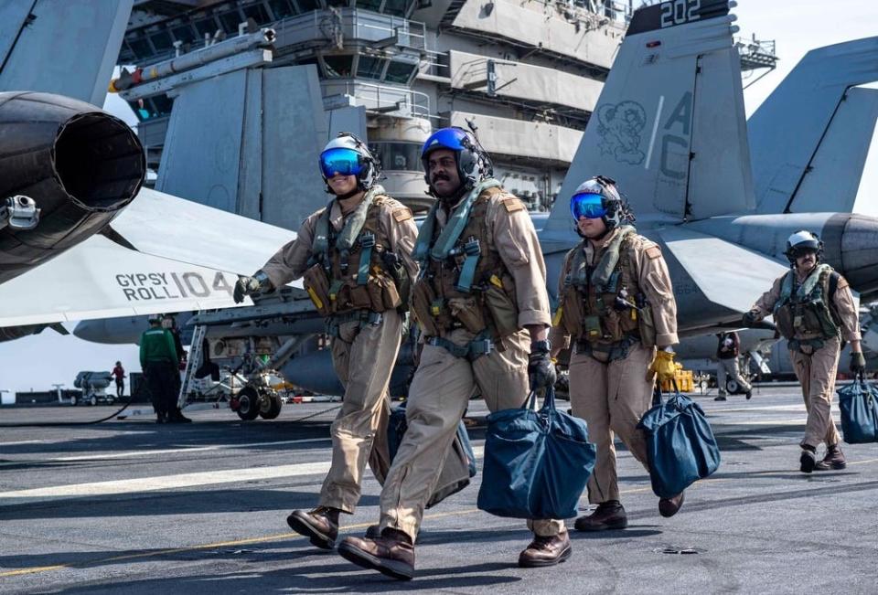 US Navy sailors walk near military aircraft while crossing the flight deck of USS Dwight D. Eisenhower
