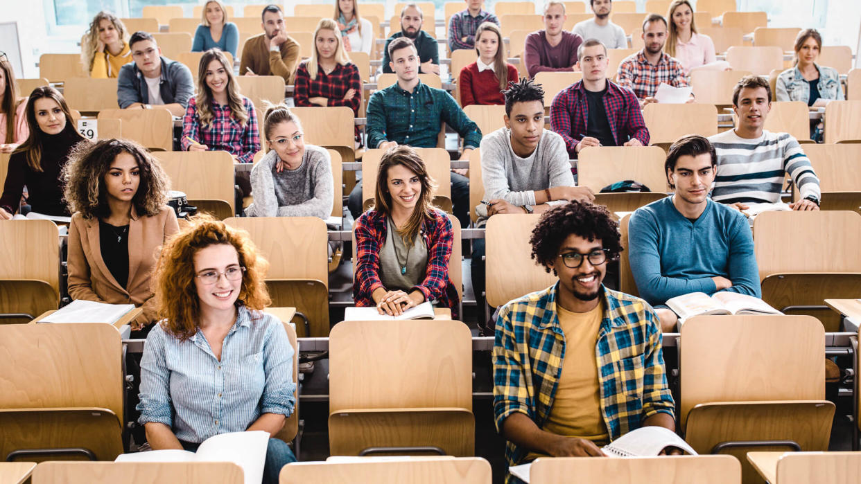 Large group of happy college students attending a class in amphitheater.