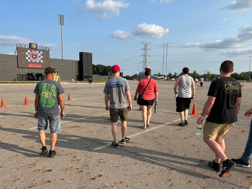 A group of racers walks the course in a vast parking lot