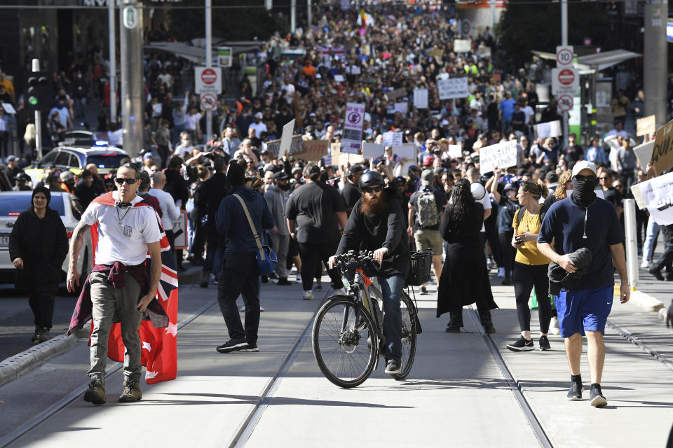 Hundreds of protesters march on a street during an anti-lockdown protest in Melbourne, Australia, Saturday, Aug. 21, 2021. Protesters are rallying against government restrictions placed in an effort to reduce the COVID-19 outbreak. (James Ross/AAP Image via AP)