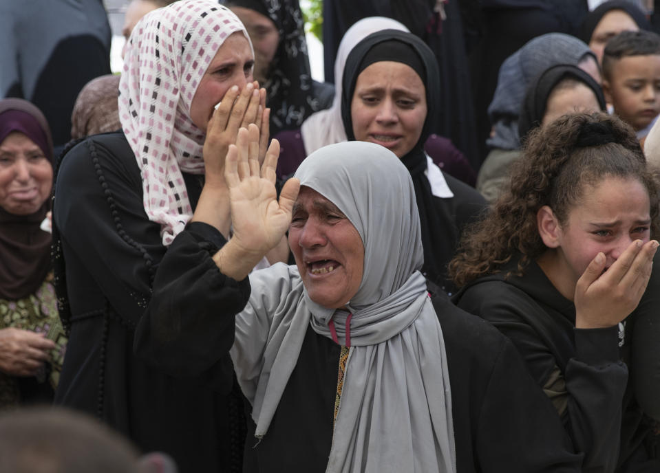 Palestinian mourners cry while taking the farewell look at the body Shaukat Awad, 20 during his funeral in the West Bank village of Beit Ummar, near Hebron, Friday, July. 30, 2021. Israeli troops shot and killed the 20 year old Palestinian man, Palestinian health officials said, during clashes that erupted in the occupied West Bank following the funeral of a Palestinian boy killed by army fire the previous day. (AP Photo/Nasser Nasser)