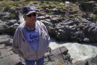 Yakama Nation elder James Kiona stands on the rocky edge of Lyle Falls on the Klickitat River, a tributary of the Columbia River, on Sunday, June 19, 2022, in Lyle, Wash. Kiona has fished for Chinook salmon for decades here on his family's scaffold, using a dip net suspended from a 33-foot pole. (AP Photo/Jessie Wardarski)