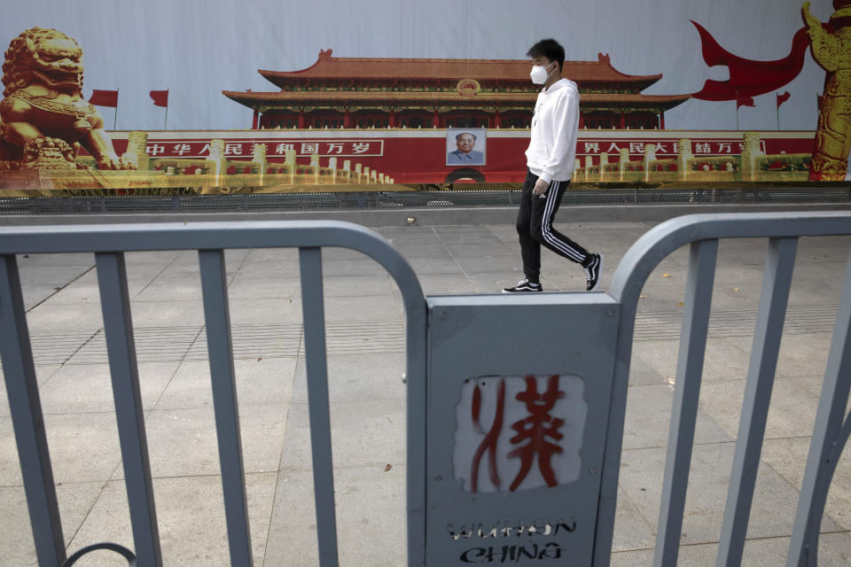 A resident wearing a mask against coronavirus walks past government propaganda poster featuring Tiananmen Gate in Wuhan in central China's Hubei province Thursday, April 16, 2020. (AP Photo/Ng Han Guan)