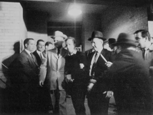 <p>Bettmann / Getty Images</p> Jack Ruby maneuvers past law enforcement and plunges forward at Lee Harvey Oswald after JFK's assassination