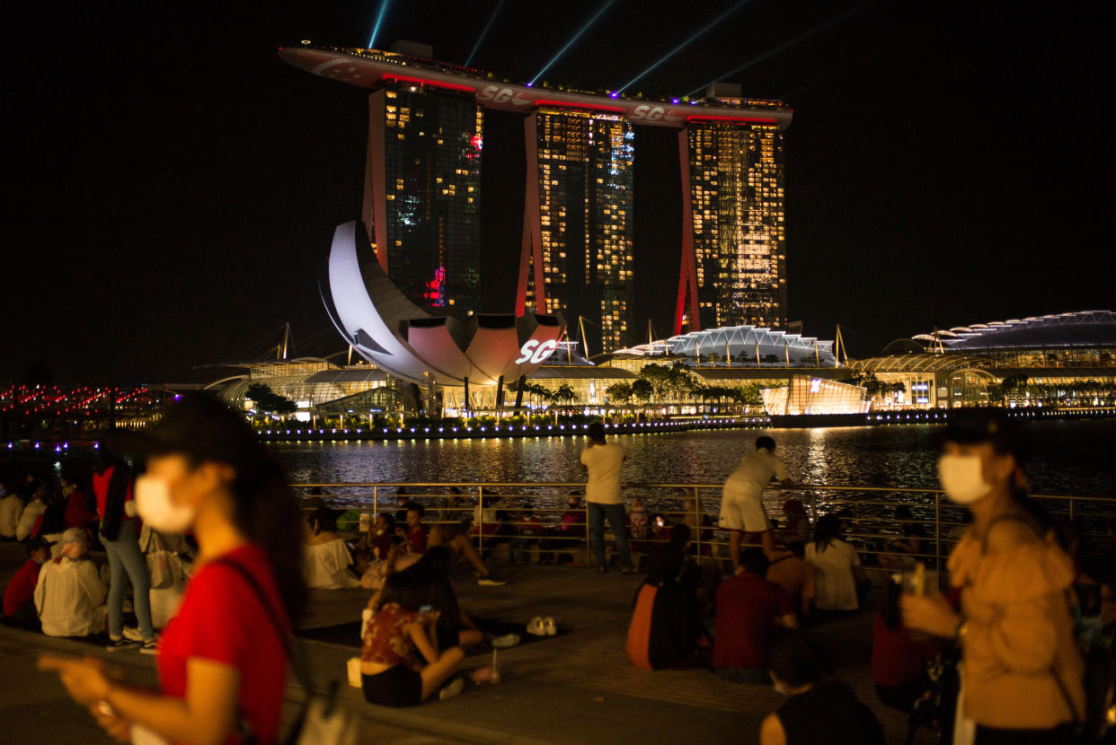 People wearing face masks wait by the Singapore River for fireworks during Singapore's National Day on 9 August, 2020. (PHOTO: LightRocket via Getty Images)