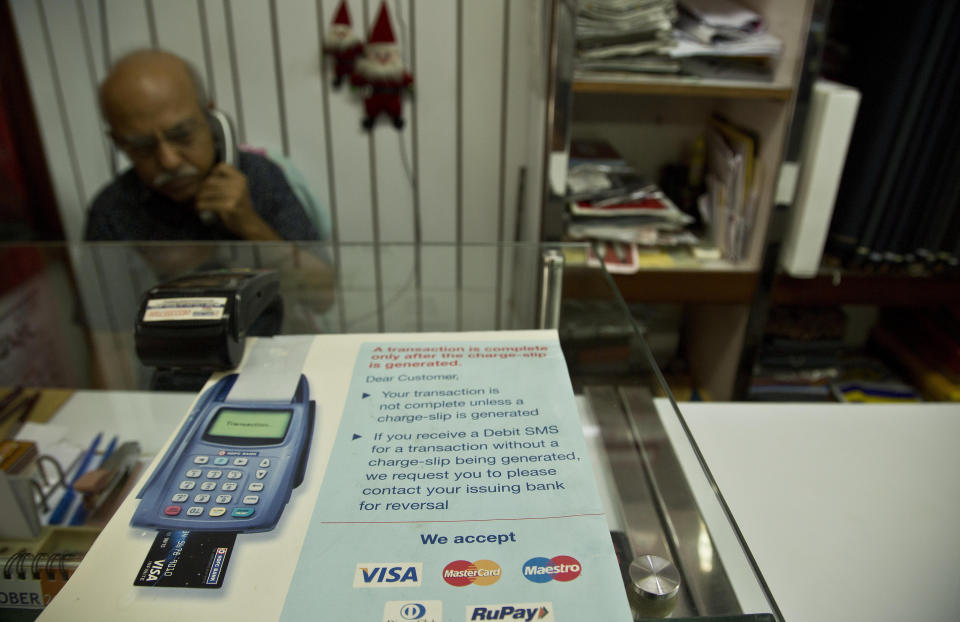 A businessman talks on phone inside his shop in Gauhati, India, Tuesday, Oct. 16, 2018. Global credit card and payments companies like American Express, Visa and MasterCard are facing a challenge in meeting a requirement to store transaction data for all Indian customers within the country. (AP Photo/Anupam Nath)