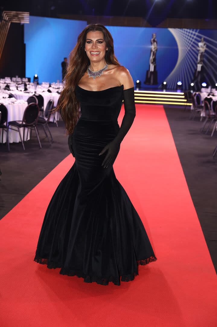 Florencia de la V se ocupó de conducir el segmento de la alfombra roja del evento, donde los personajes centrales de la radio local charlaron con la prensa y mostraron sus looks. Antes de comenzar, mostró su propio look: un vestido largo de terciopelo negro de Adrián Brown de corte sirena y escote palabra de honor. Además, la conductora de América acompañó su outfit con guantes negros transparentes, maquillaje de Mabi Autino y una gargantilla de Santino