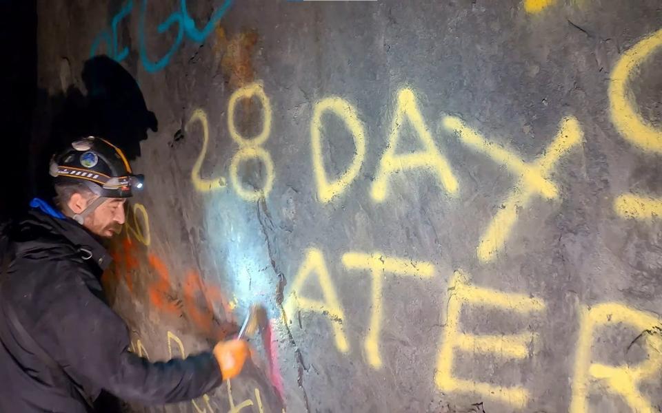 A volunteer cleans graffiti inside the cave