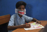 A student attends a class wearing a handmade paper mask to protect himself from the wide spread of coronavirus in a government school in Hyderabad.