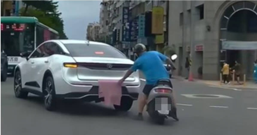 1輛白色轎車車牌被毛巾蓋住，1位阿伯騎車快速將毛巾抽走。（圖／擷取自WoWtchout—地圖型行車影像分享平台YouTube頻道）