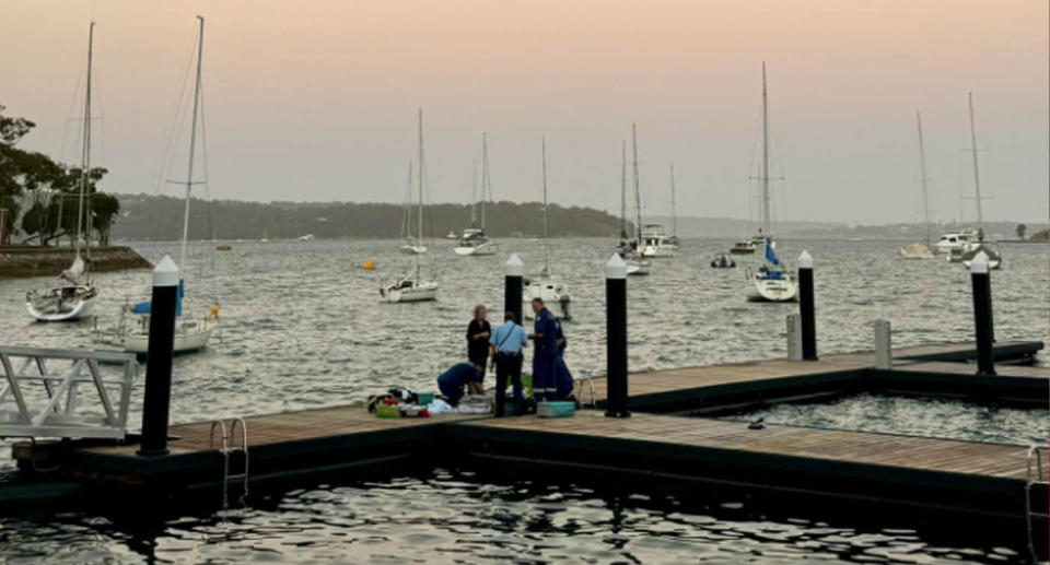 Paramedics attend to a woman on a wharf at Elizabeth Bay.