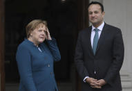 Irish Prime Minister Leo Varadkar looks the media while German Chancellor Angela Merkel adjusts her hair as they pose at the entrance Farmleigh House for the media in Dublin, Ireland, Thursday, April 4, 2019. (AP Photo/Peter Morrison)