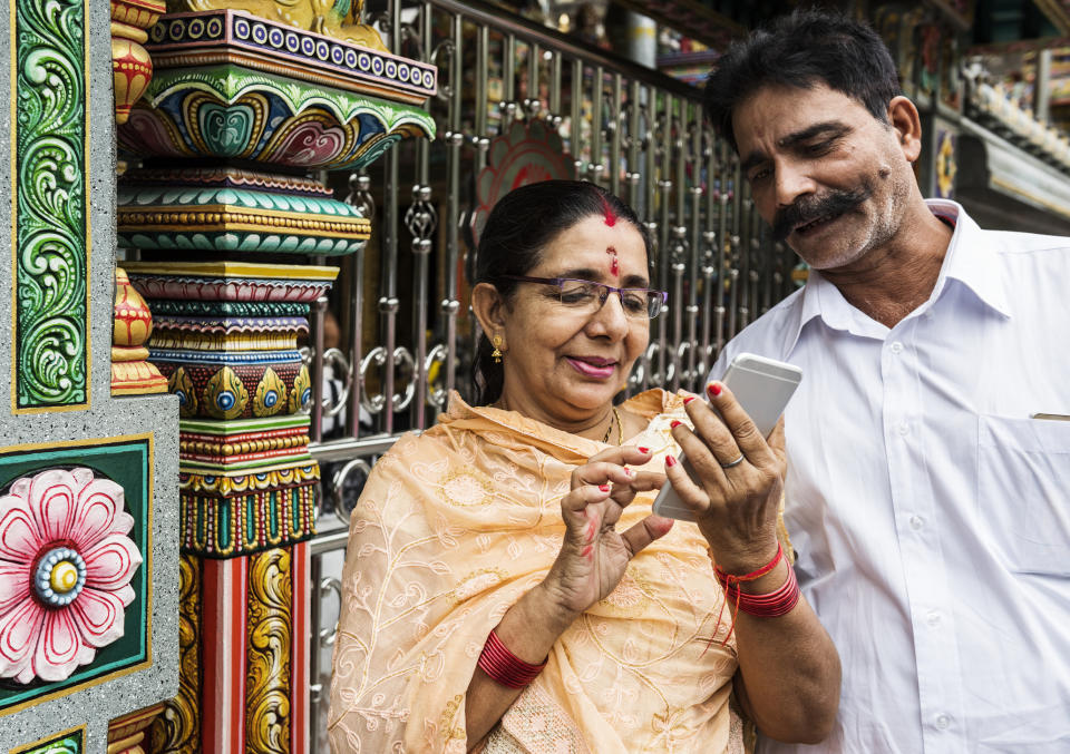 Indian woman using a smartphone while a man looks at the screen