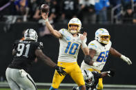 Los Angeles Chargers quarterback Justin Herbert (10) passes under pressure from Las Vegas Raiders defensive tackle Bilal Nichols (91) during the second half of an NFL football game, Sunday, Dec. 4, 2022, in Las Vegas. The Raiders won 27-20. (AP Photo/Matt York)