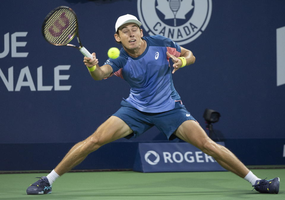 Alex de Minaur, of Australia, slides for the ball during his first-round match against Denis Shapovalov, of Canada, at the National Bank Open tennis tournament in Montreal, Monday, Aug. 8, 2022. (Graham Hughes/The Canadian Press via AP)