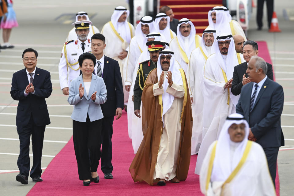 In this photo released by Xinhua News Agency, Kuwait's Crown Prince Sheikh Meshal Al Ahmed Al Jaber Al Sabah, center, applauds with Chinese officers as he was welcomed by young performers upon the arrival in Hangzhou, China, Thursday, Sept. 21, 2023. Kuwaiti crown prince arrived in Hangzhou to attend the opening ceremony of the 19th Asian Games. (Huang Zongzhi/Xinhua via AP)