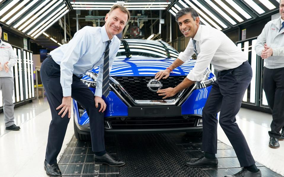 Rishi Sunak and Jeremy Hunt attach a Nissan badge to a car as they visit the car manufacturer's factory in Sunderland this morning