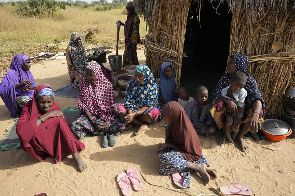 Aisha Ali, 40, right, is joined by other woman mourning her four dead children in Darayami, northeastern Nigeria, Wednesday Oct. 26, 2022. When floodwaters reached her hut made of woven straw mats and raffia palms, Aisha packed up what belongings she could and set off on foot with her eight youngest children. "While the flood was trying to destroy things, we were trying to save ourselves," she said. Only four of her children survived.(AP Photo/Sunday Alamba)